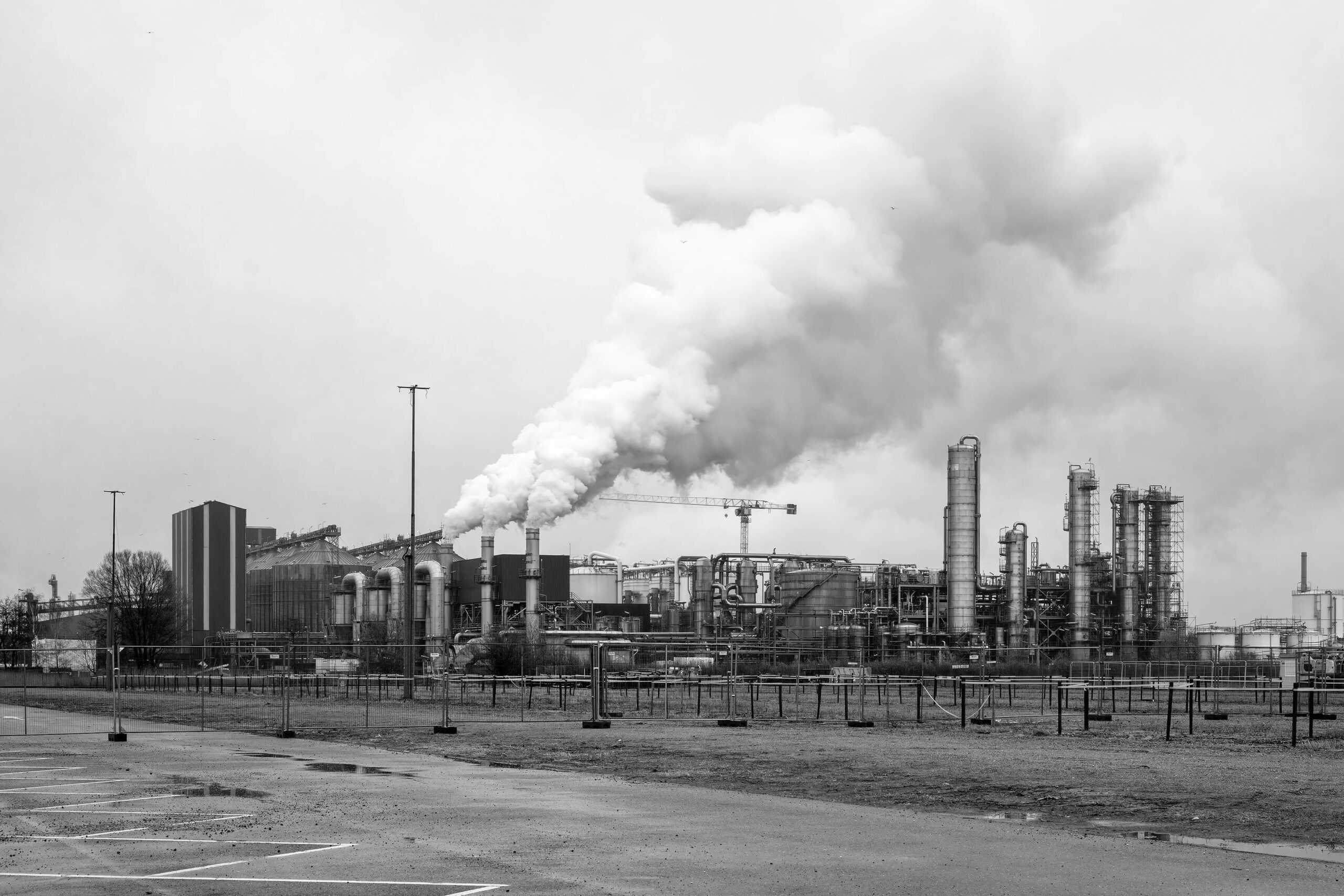 Oil refinery and smoking chimneys in black and white at Maasvlakte Europoort Rotterdam industrial harbour area.