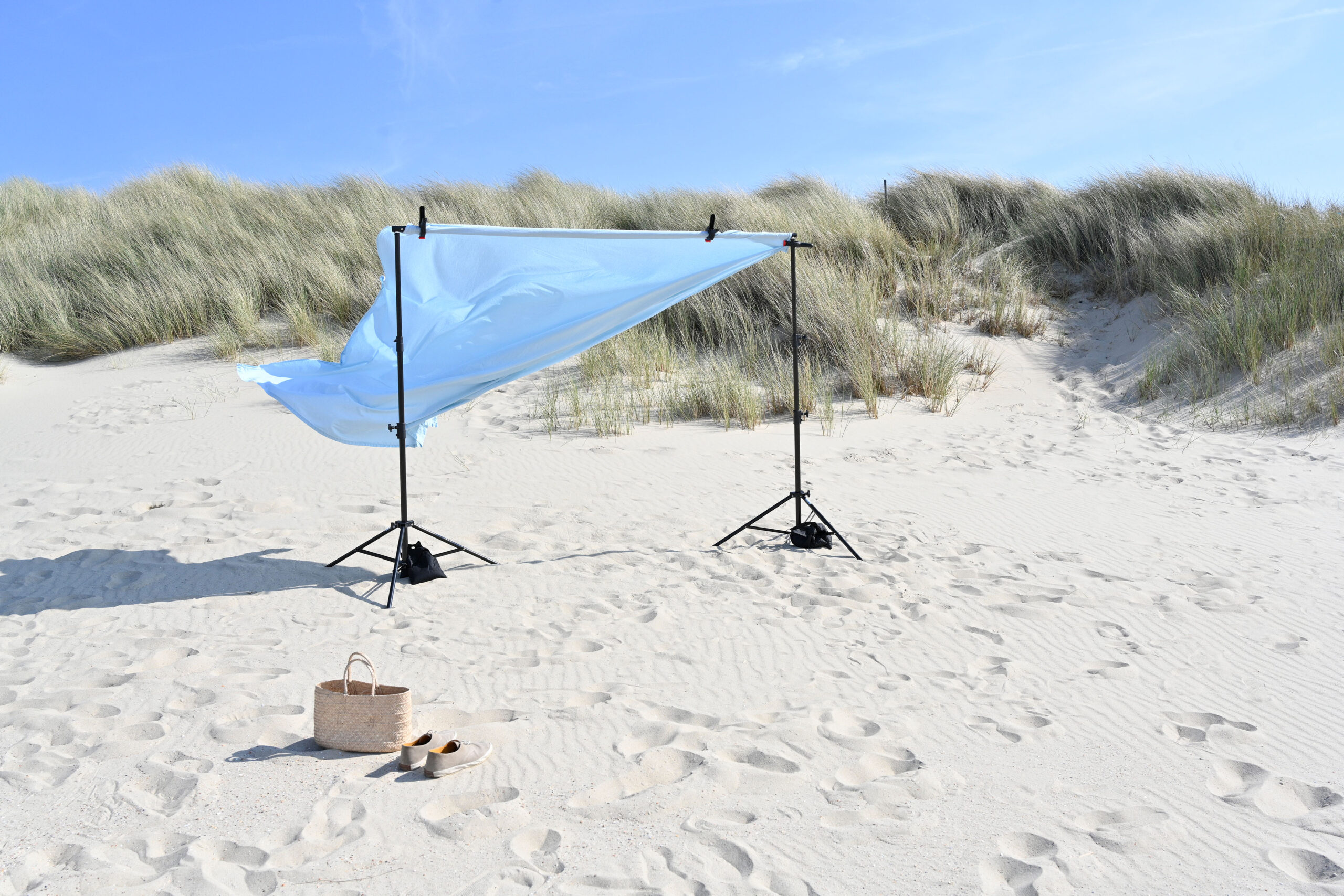 A blue backdrop during a fashion shoot in summer blowing in the wind in Bergen aan Zee, a beautiful village along the North Sea coast in the Netherlands. Bergen's white sandy beach with high grassy dunes stretches for miles.