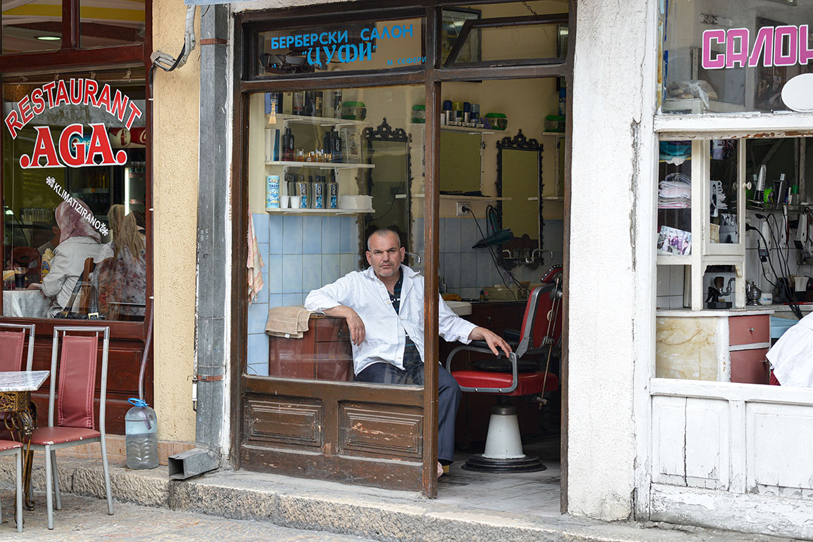 Barber in window, waiting for a client in Skopje, North Macedonia.